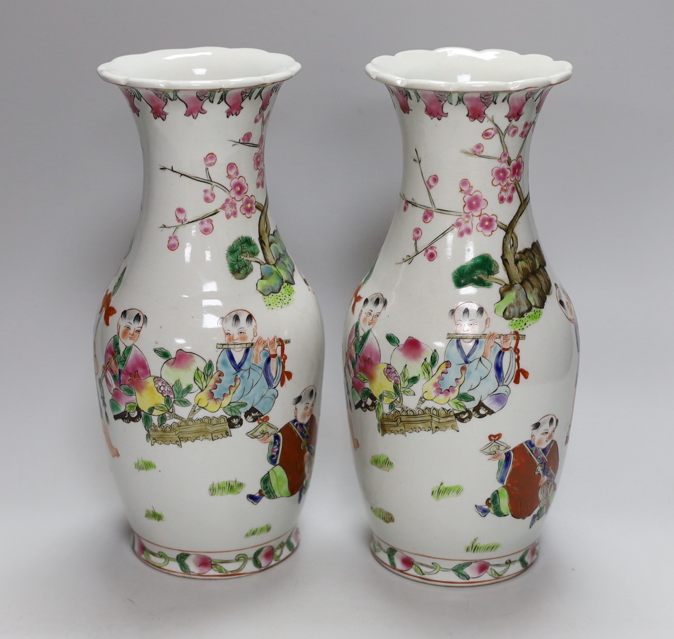 A pair of Chinese Famille Rose ‘boys’ vases, 25cms high